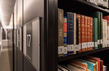 A side view of an AKC library shelf with some Arabic books placed in a single pile